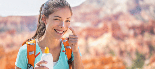 Woman applying sunscreen while hiking outdoors